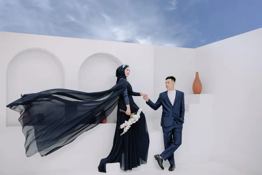 Foto prewedding Kak Upi dan pasangan di antara dinding putih berlengkung.